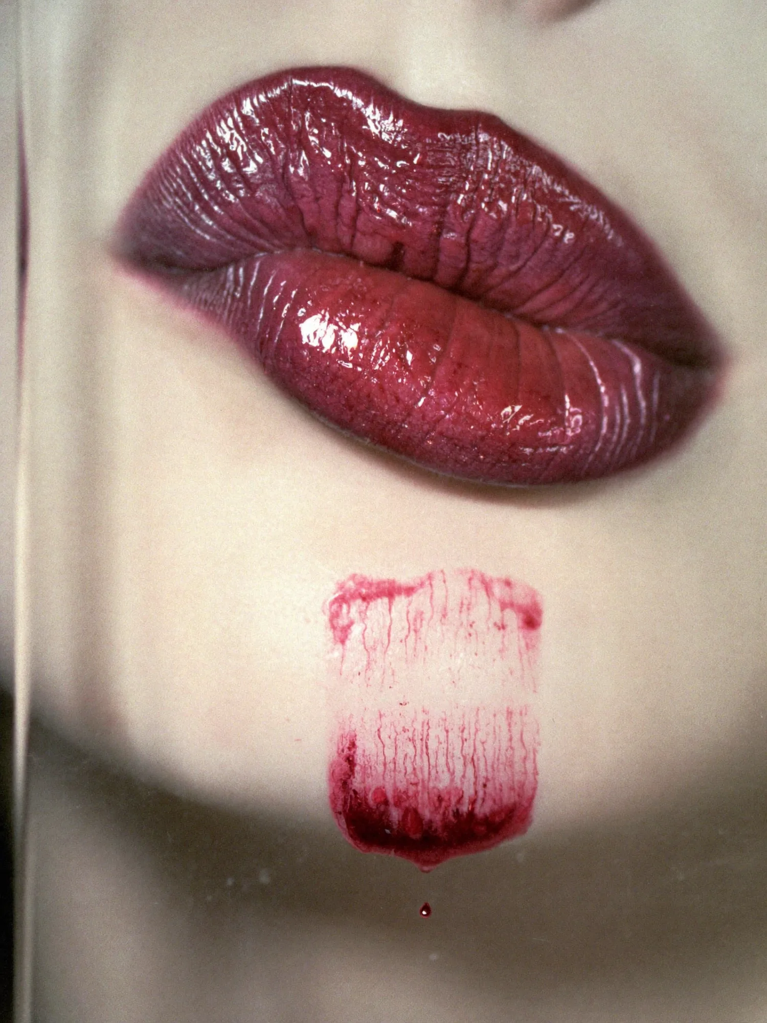 A glossed plum lip with a swatch drawn down the chin