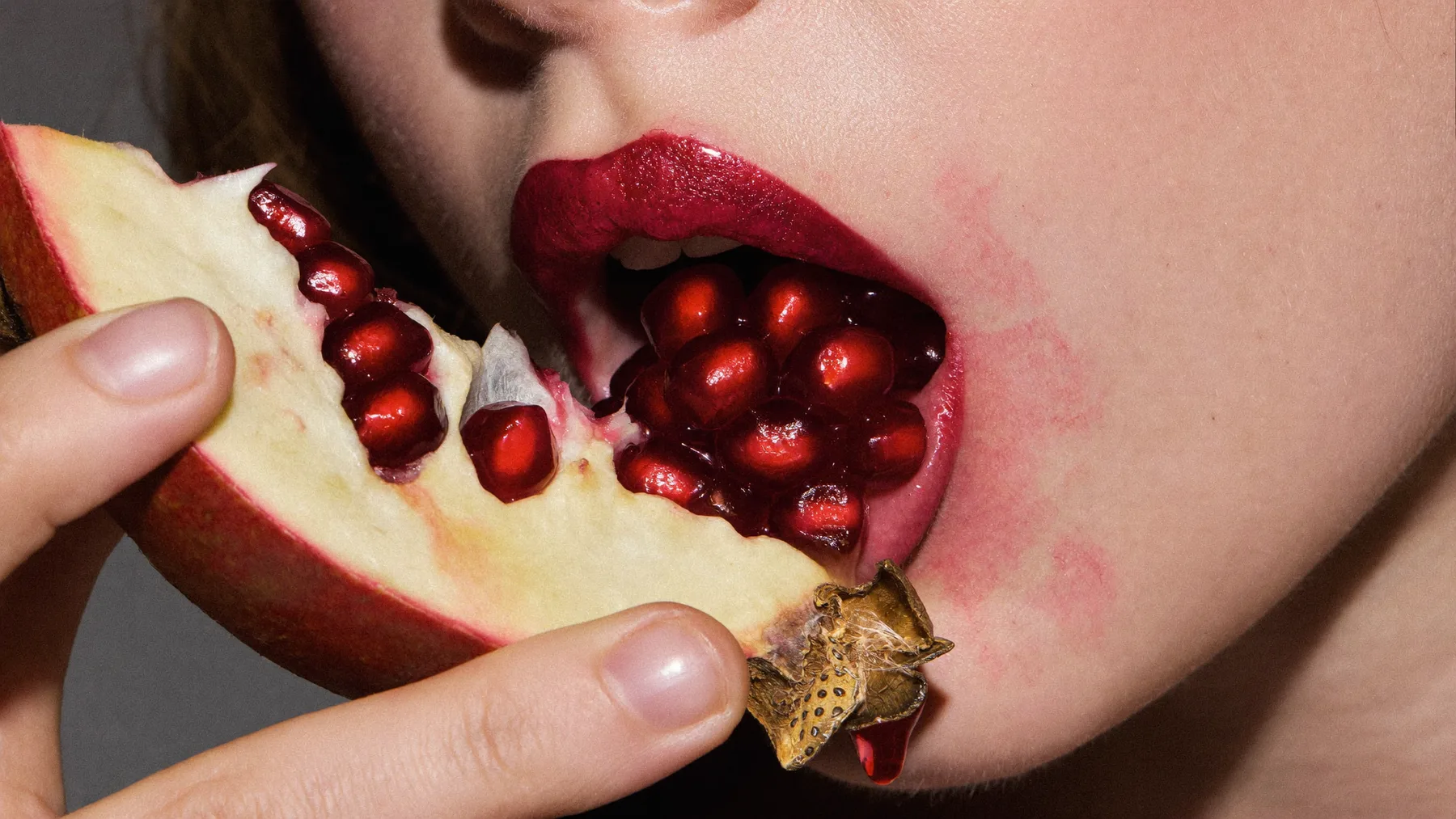 Pomegranate seeds against a glossed lip
