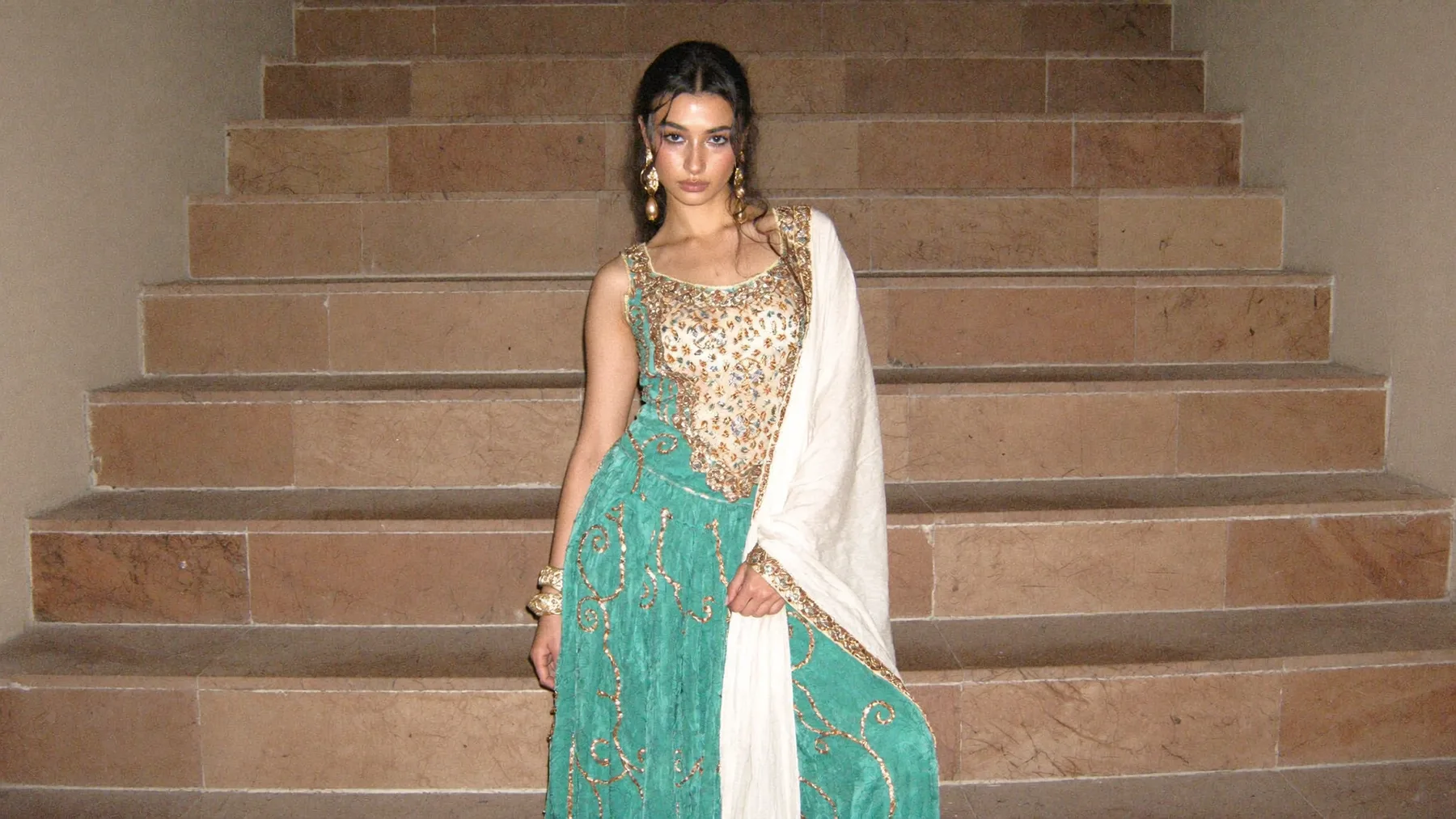 A teal lehenga and ivory dupatta on a marble stair, direct flash