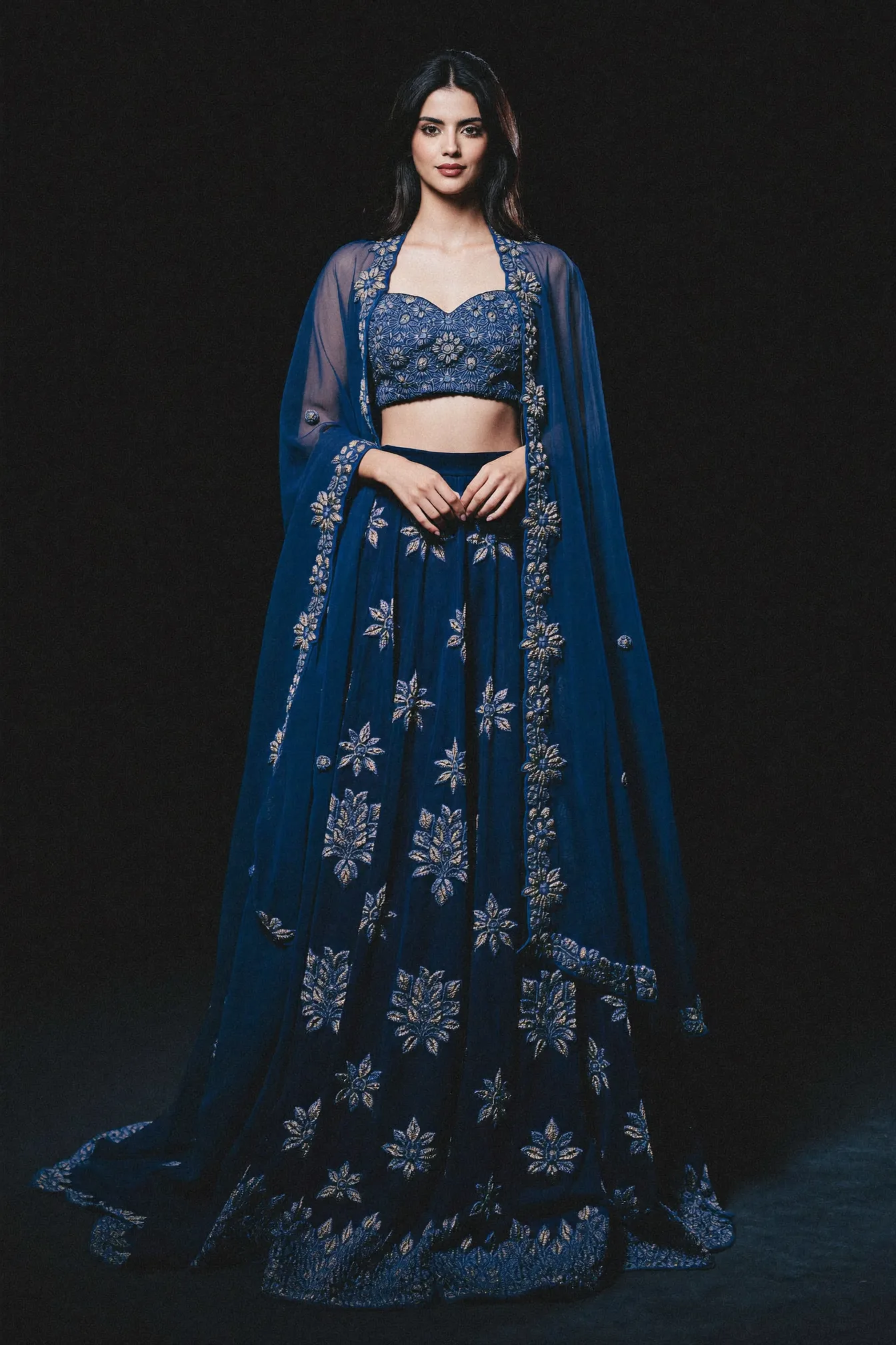 An indigo velvet lehenga and sheer cape worked in silver floral sprigs